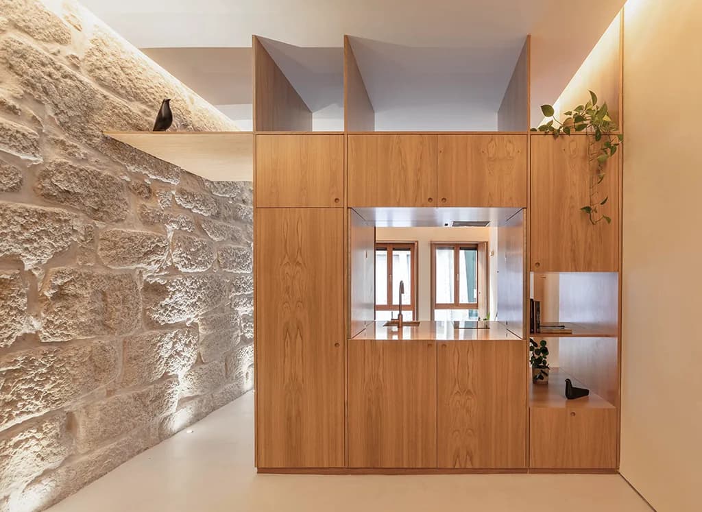 An oak volume set against an exposed granite wall, by Rita Bessa Arquitectura